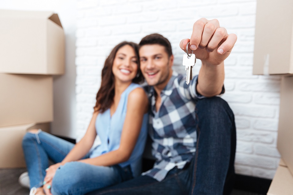 Young married couple with boxes and holding flat keys